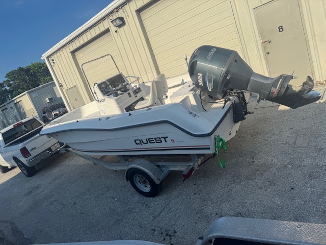 White Quest center console boat with a Yamaha outboard parked on a trailer outside the Harper Marine Services shop after service work.